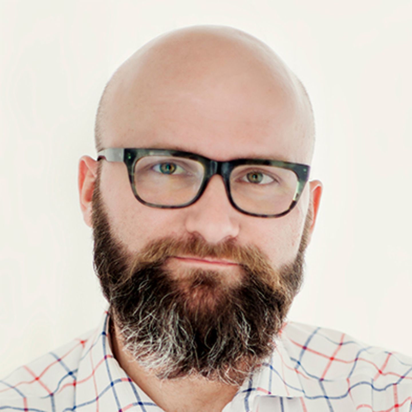 Dr. hab. Tomasz Piekot, purtând o cămașă în carouri, se sprijină de un perete cu brațele încrucișate