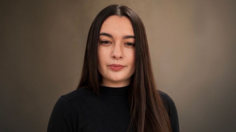 Daniela Moaca, Senior Manager IT la EOS Romania, fotografie portret cu pulover pe gât de culoare întunecată.