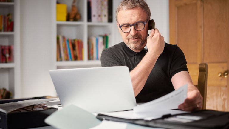 Midaged man talking on the phone to clarify his debt collection