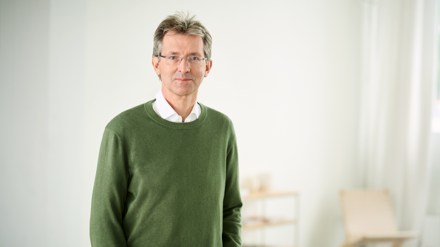 Justus Hecking-Veltman, CFO, cu pulover verde și cămașă albă, stând într-o cameră luminoasă.