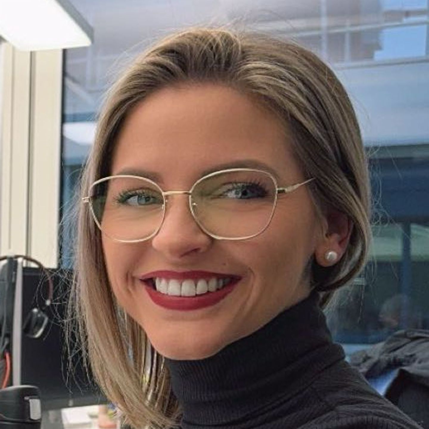 Genny Bollinger, specialist în restructurare a datoriilor la EOS din Elveția, stă la biroul ei, îmbrăcat cu un pulover gri cu gât și zâmbește camerei.
