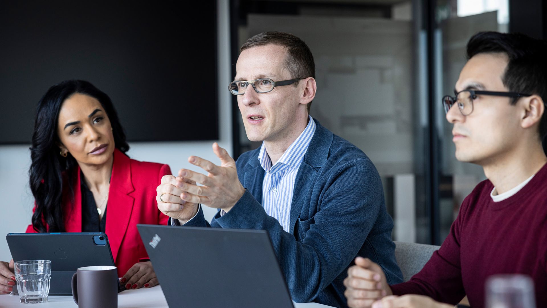 Trei persoane poartă o conversație într-un birou.